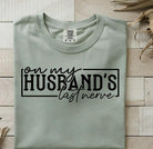 On My Husband's Last Nerve graphic tee by Anchored Grace Boutique, featuring humorous text on a casual cotton t-shirt.