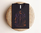 Practical Magic neon graphic tee from Anchored Grace Boutique featuring a vibrant, colorful design on a black cotton t-shirt.