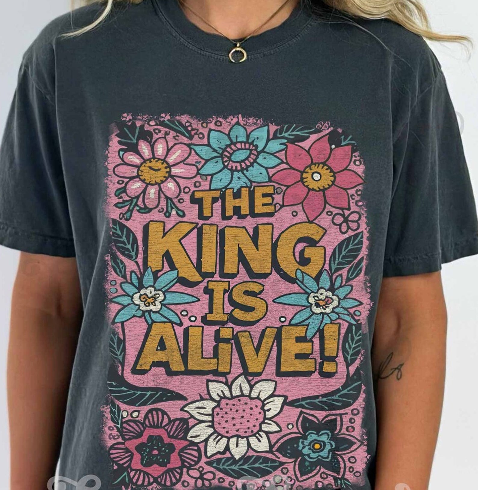 Black graphic tee with "The King is Alive" print from Anchored Grace Boutique, featuring a casual fit and bold text design.