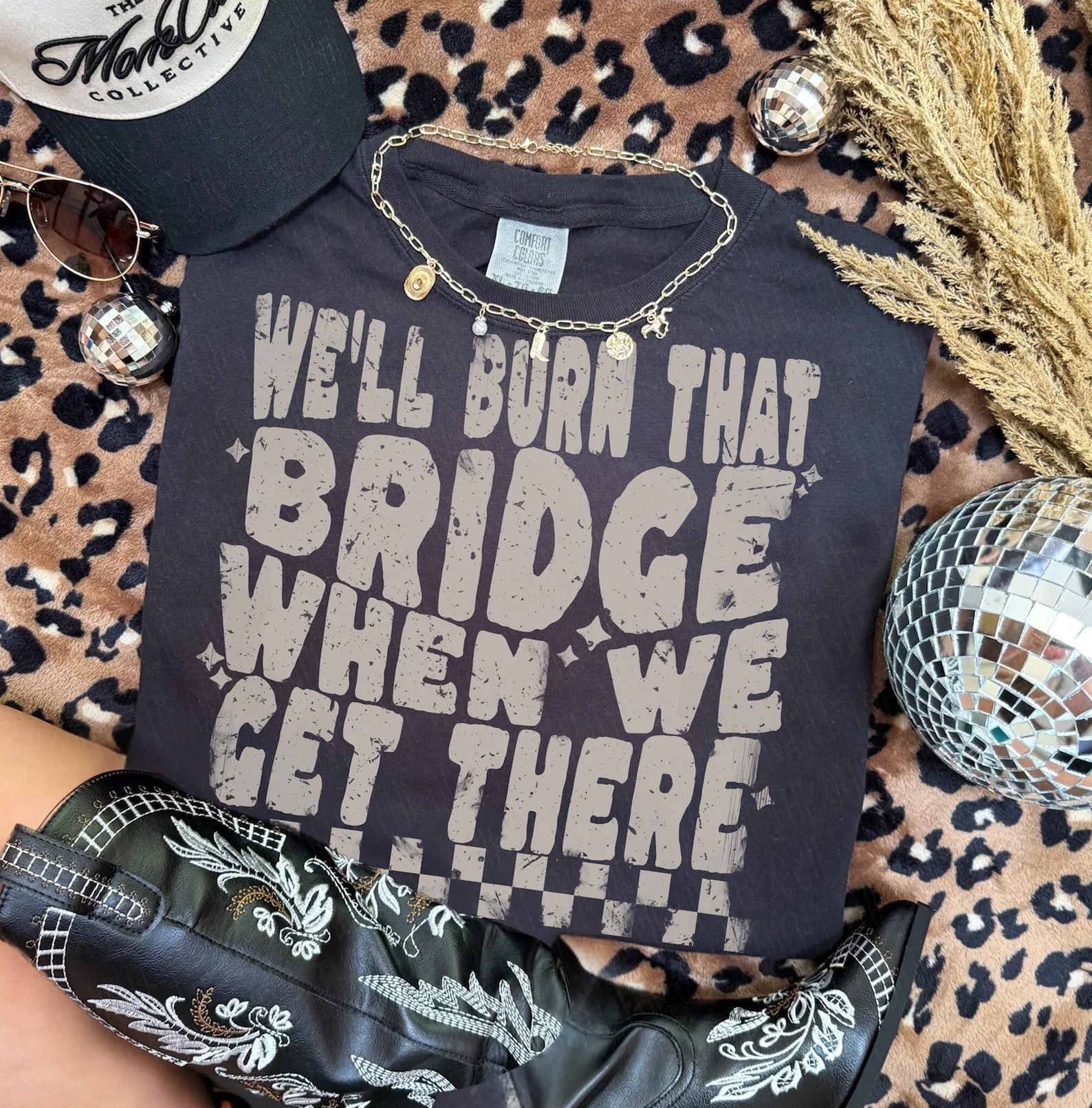 Black graphic tee from Anchored Grace Boutique featuring the phrase "We'll Burn That Bridge When We Get There" in bold white lettering.
