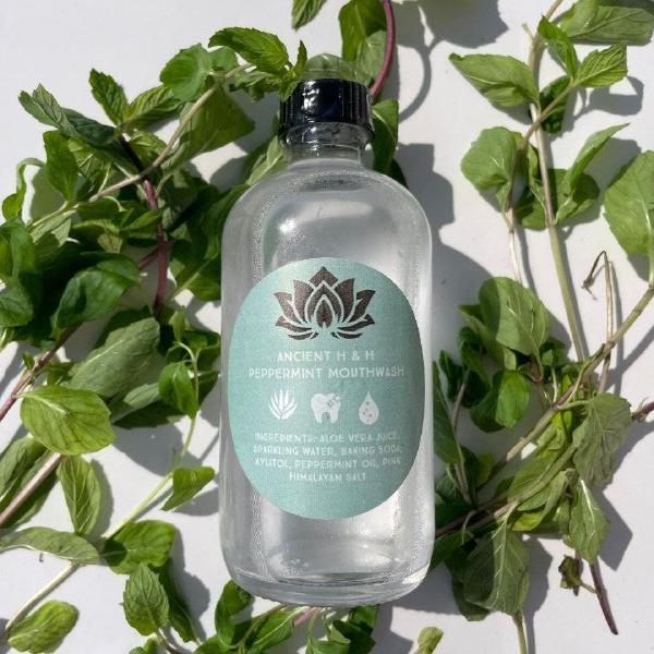 Bottle of Ancient Health & Healings peppermint mouthwash showing the label and clear liquid inside.