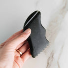 Black nephrite Gua Sha lifting tool by Annmarie Skin Care, used for facial massage and skincare routines.