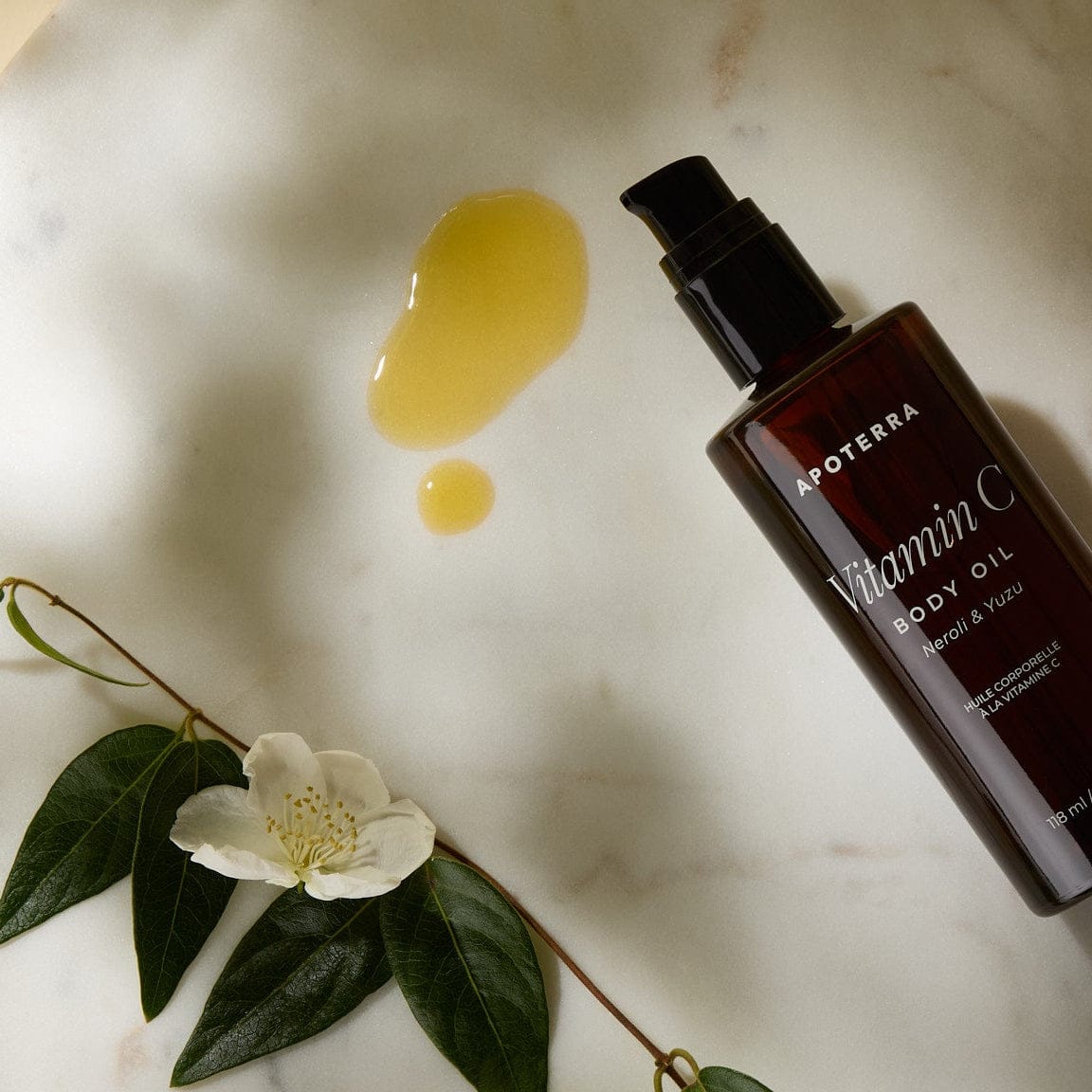 Apoterra Vitamin C Body Oil with neroli and yuzu for nourishing bath and body skincare, featuring a clear bottle with orange-colored oil.