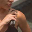 Woman applying Apoterra Vitamin C Body Oil in a bath and body setting, highlighting the nourishing skincare product.