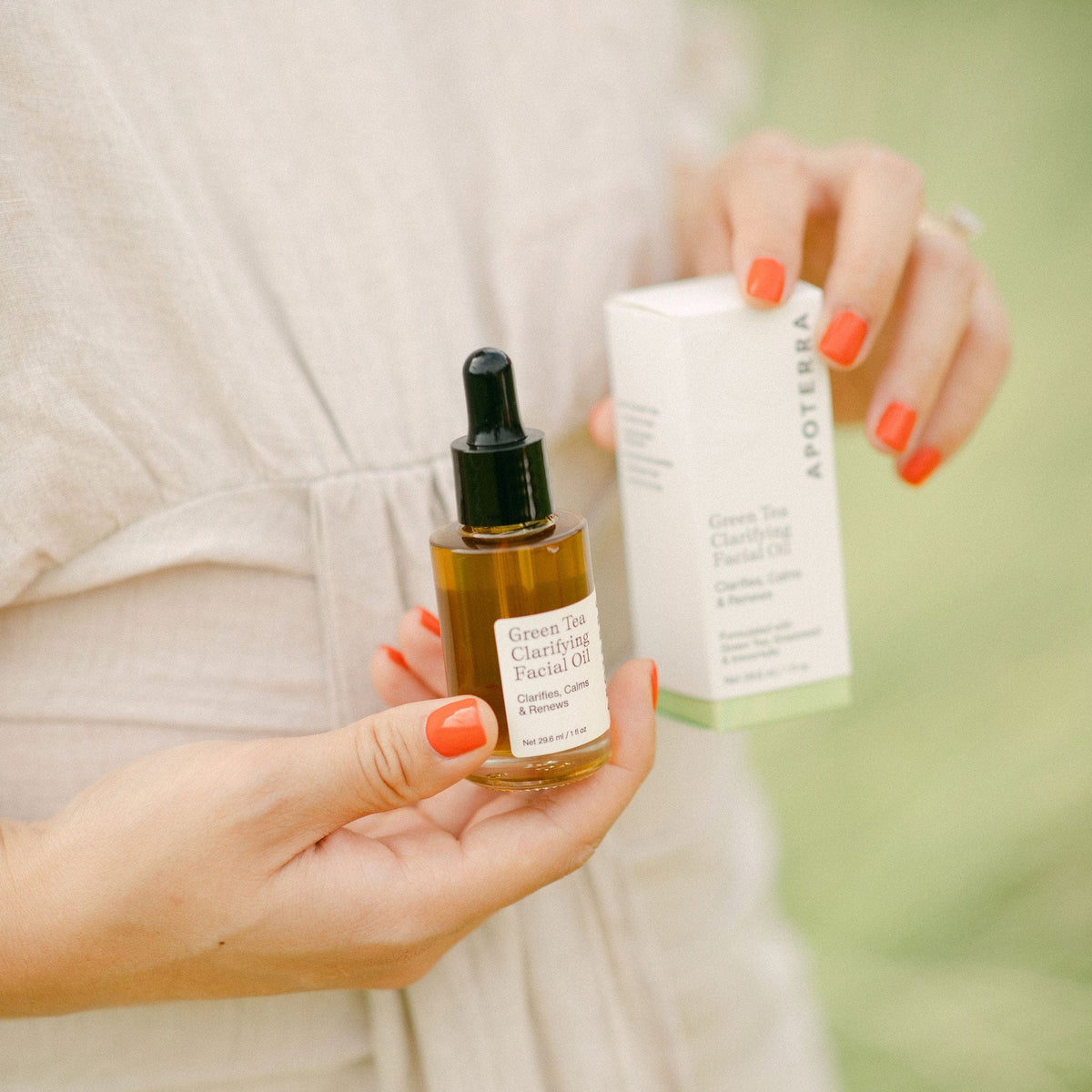 Hands holding Apoterra Green Tea Clarifying Facial Oil, a natural herbal facial oil for skin clarity and soothing hydration.