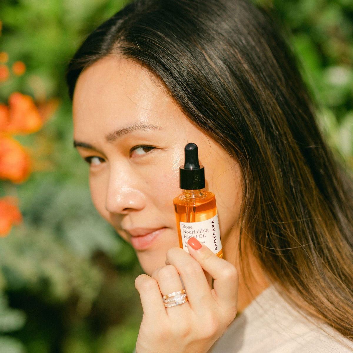 Apoterra Rose Nourishing Facial Oil bottle in sunlight, highlighting natural skincare for glowing, hydrated skin.