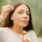 Woman applying Apoterra Rose Nourishing Facial Oil, showcasing the natural skincare product for glowing skin.