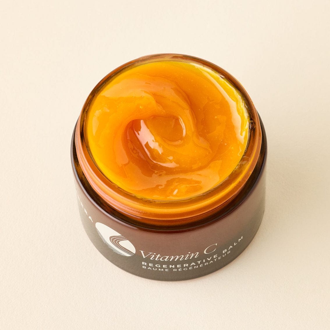 Apoterra Vitamin C Regenerative Facial Oil balm jar with orange-tinted balm and natural ingredients visible on top.