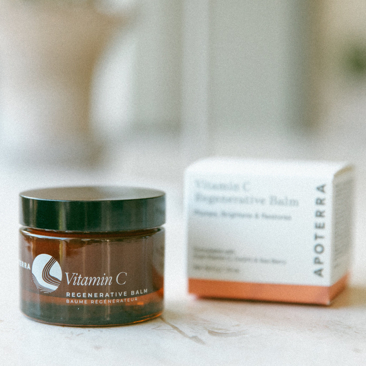 Apoterra Vitamin C Regenerative Balm facial oil in a box, featuring a sleek container with vibrant citrus-inspired packaging.