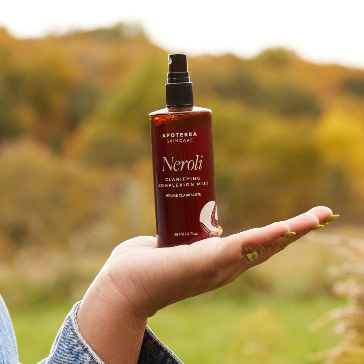 Apoterra Neroli Clarifying Complexion Mist toner held in hand, featuring a spray bottle with fresh botanical ingredients.