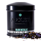 Black metallic tin of Violet Elderberry Black Tea by August Uncommon Tea, showcasing the elegant packaging and rich tea blend.