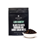 Black tea in a 28-cup tin, Low Country Bourbon Sugar Black Tea by August Uncommon Tea, with tea leaves and packaging visible.