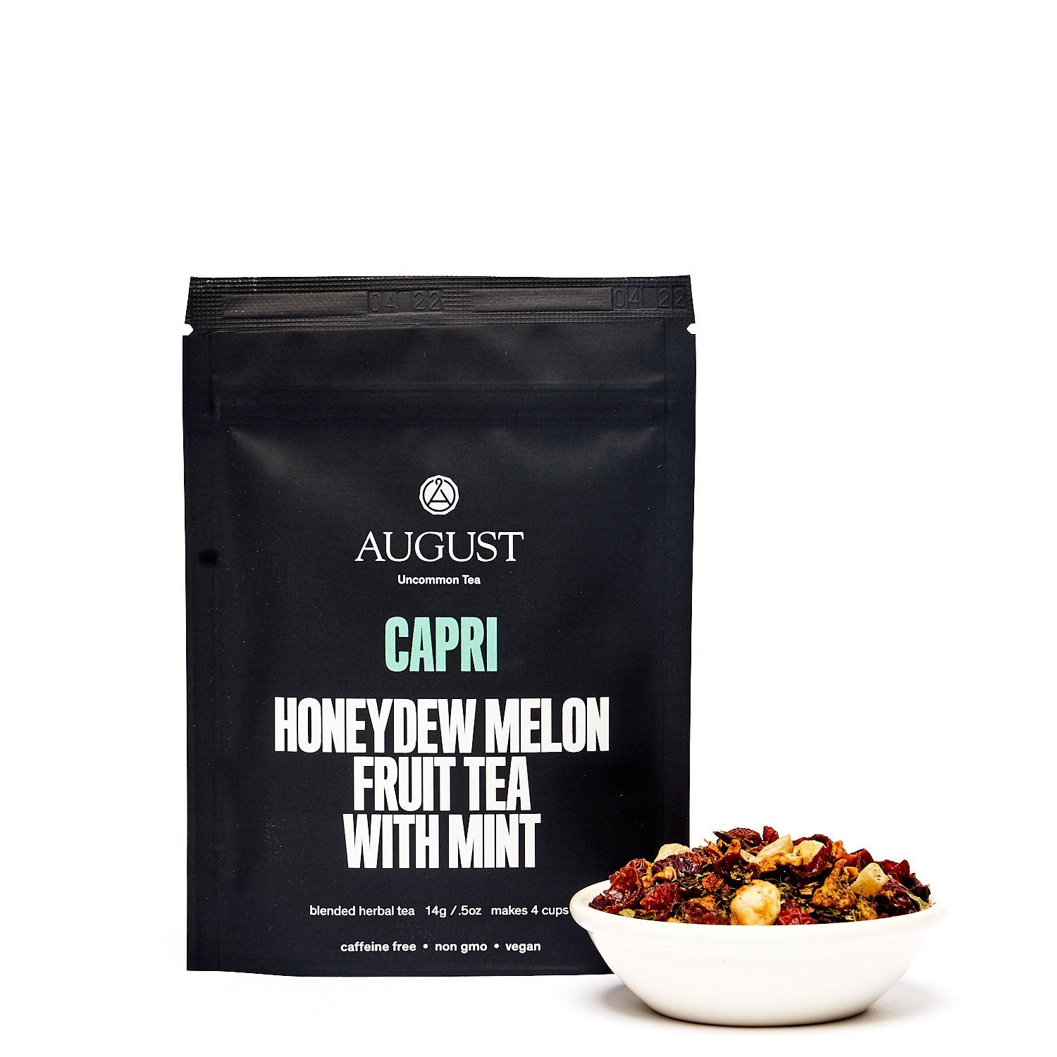 Cup of August Uncommon Tea Capri Honeydew Melon Mint herbal tea in a tea bag, caffeine-free, with fresh honeydew melon and mint leaves.