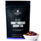 August Uncommon Mojave Smoky Hibiscus Cherry Tea in a 15-cup herbal tea bag, low caffeine, vibrant red tea leaves and cherry blossoms.