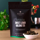 Sweet Lemon Oolong Green Tea by August Uncommon Tea in a 15-cup bag, showcasing fresh lemon and green tea leaves.