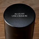 Dark roasted Taiwanese oolong tea leaves in a 150g tin, featuring rare black pearl leaves from August Uncommon Tea.