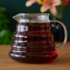 Two cup glass teapot by August Uncommon Tea, showcasing clear glass design with a removable infuser and a sturdy handle.