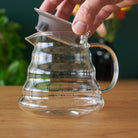 Two Cup Glass Teapot by August Uncommon Tea showing clear glass body, handle, spout, and lid for brewing tea.