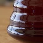 Two cup glass teapot by August Uncommon Tea featuring a clear design, stainless steel lid, and two matching teacups for brewing and serving.