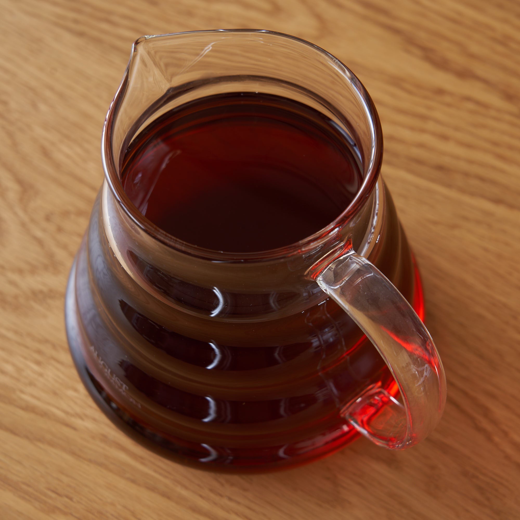 Two cup glass teapot by August Uncommon Tea, showcasing clear glass body and stainless steel lid for brewing tea.