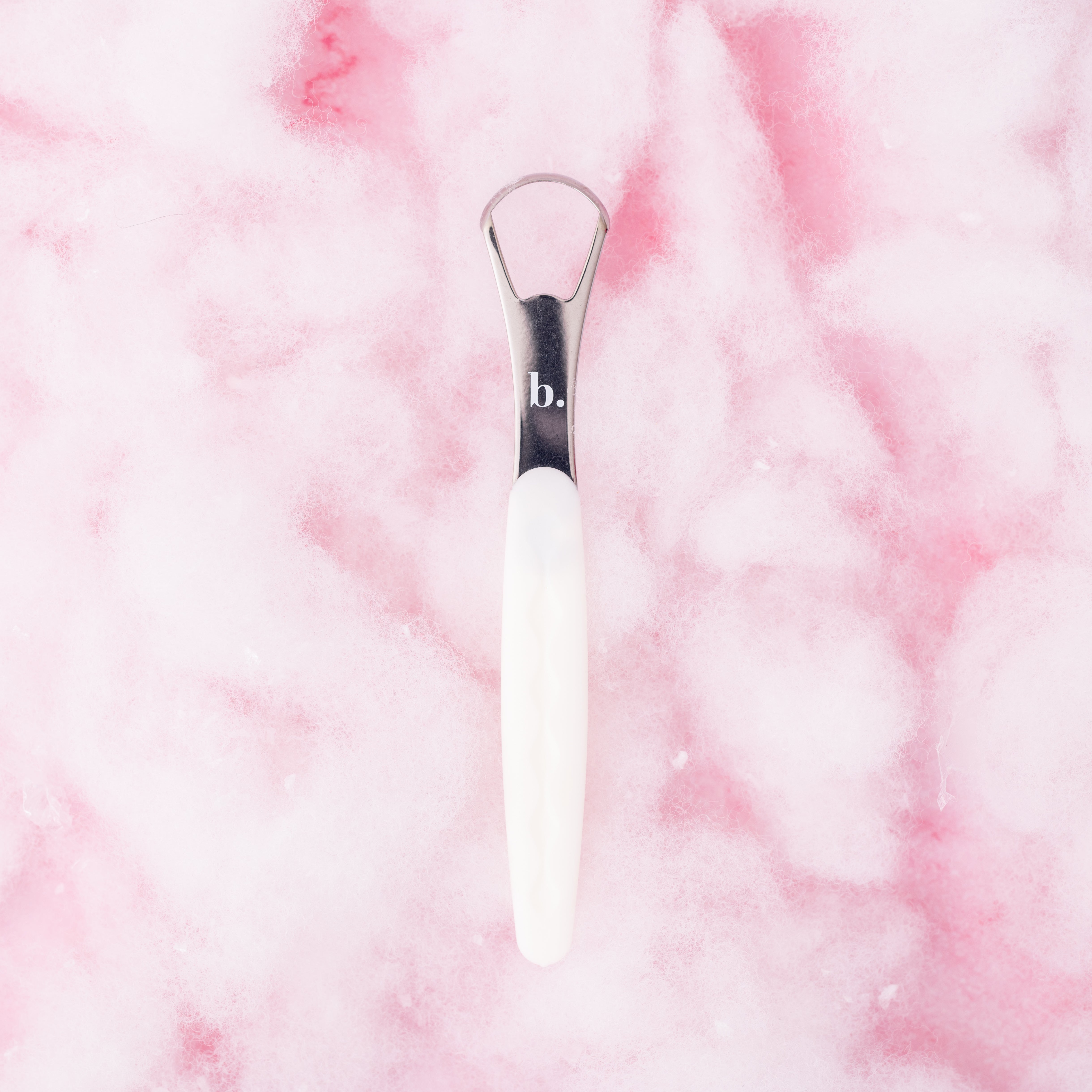 Pink tongue scraper by beaut.beautyco with a smooth handle and textured scraping surface for oral hygiene.