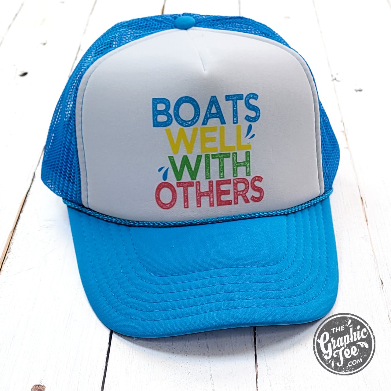Neon blue and white foam trucker cap with "Boats Well With Others" graphic, casual style, by The Graphic Tee.