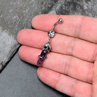 Purple Amethyst Skull Obelisk dangle belly ring by BodyCandy featuring a rose-shaped design and a dangling skull ornament.