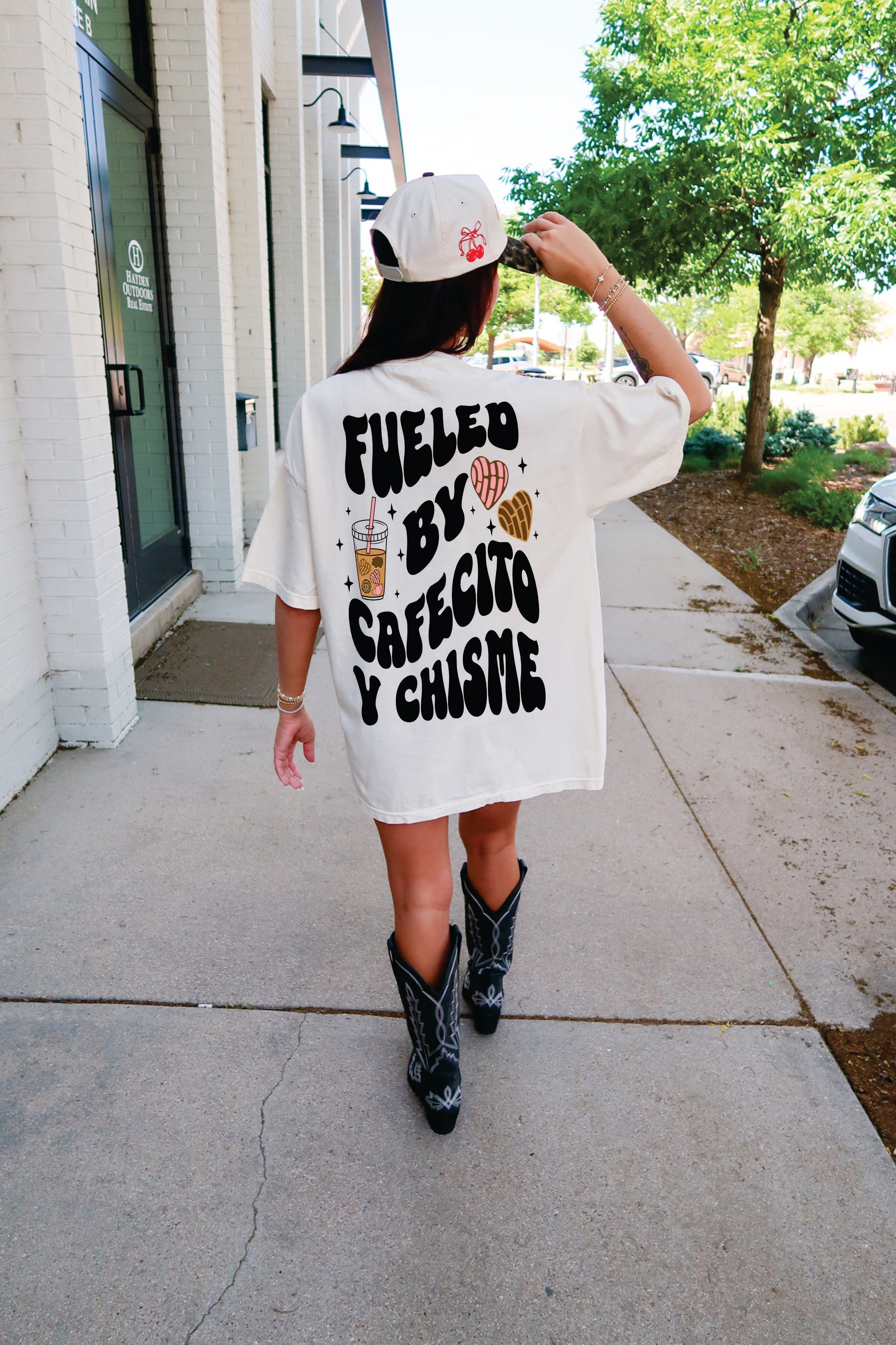 Model wearing a Cafecito y Chisme t-shirt by Shop Karma Tees, showcasing the vibrant design on the front.