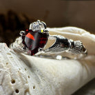 Celtic Crystal Design Jewelry Garnet Claddagh ring with intricate Celtic knot detailing and a central garnet gemstone.