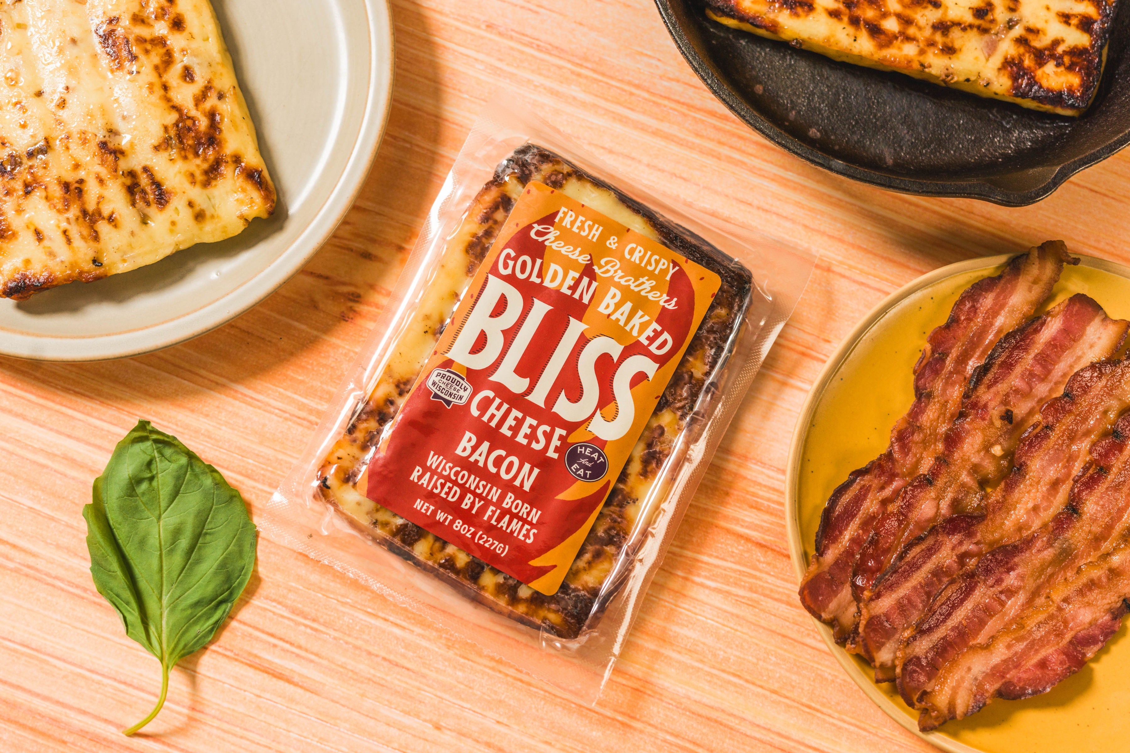 Golden baked Bliss cheese with bacon from Cheese Brothers, Inc., showing melted cheese topped with crispy bacon pieces.