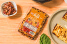 Golden baked Bliss cheese with crispy bacon pieces from Cheese Brothers, Inc., showcasing a cheesy baked snack with bacon bits.