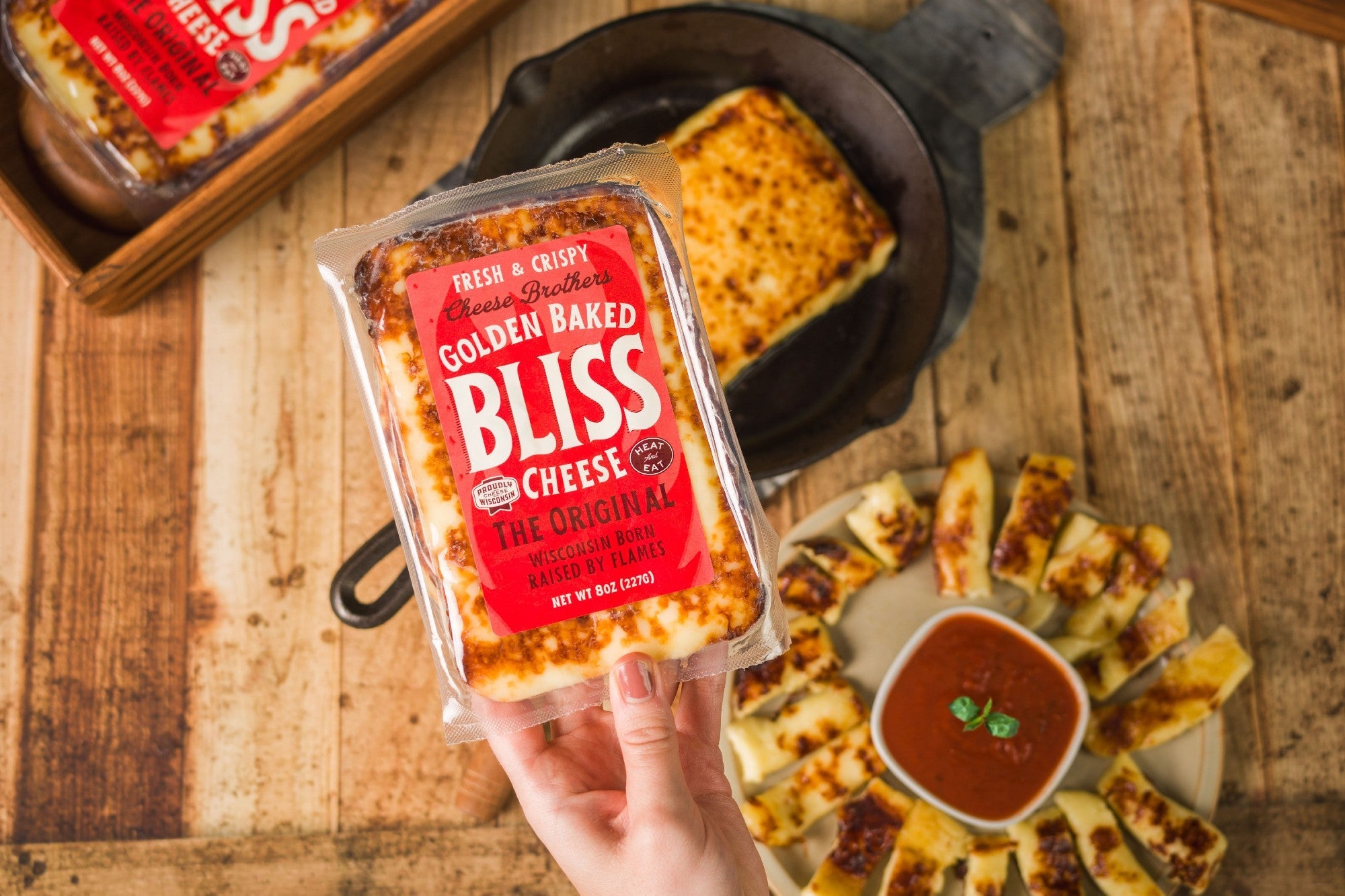 Golden Baked Bliss Cheese from Cheese Brothers, Inc. melted and baked with a crispy golden crust, showcasing its creamy cheese interior.