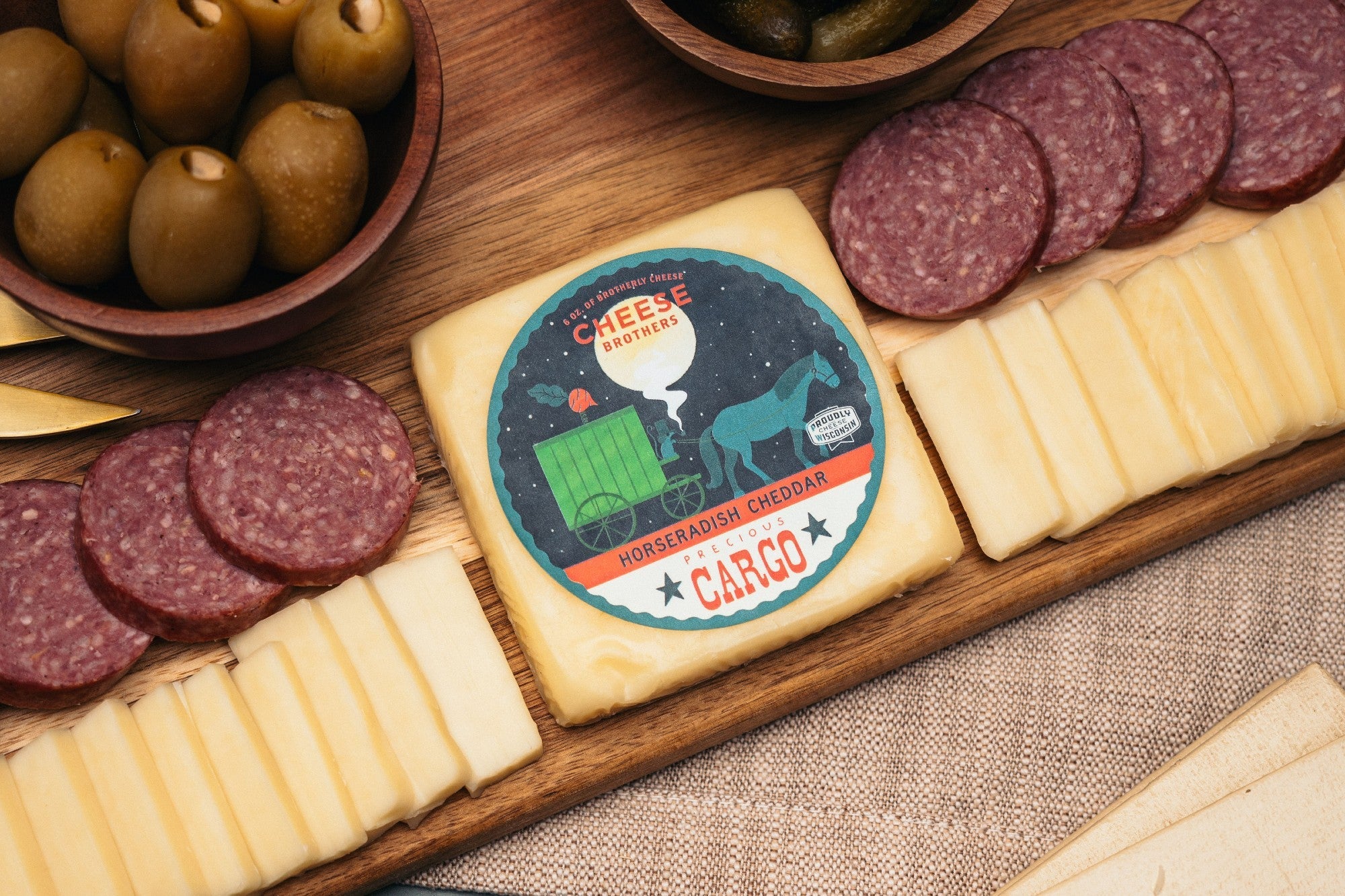 A block of Precious Cargo Horseradish Cheddar cheese from Cheese Brothers, Inc., showcasing its rich texture and marbled appearance.