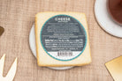 Slice of Precious Cargo horseradish cheddar cheese from Cheese Brothers, Inc., showing its marbled texture and spicy horseradish flavor.