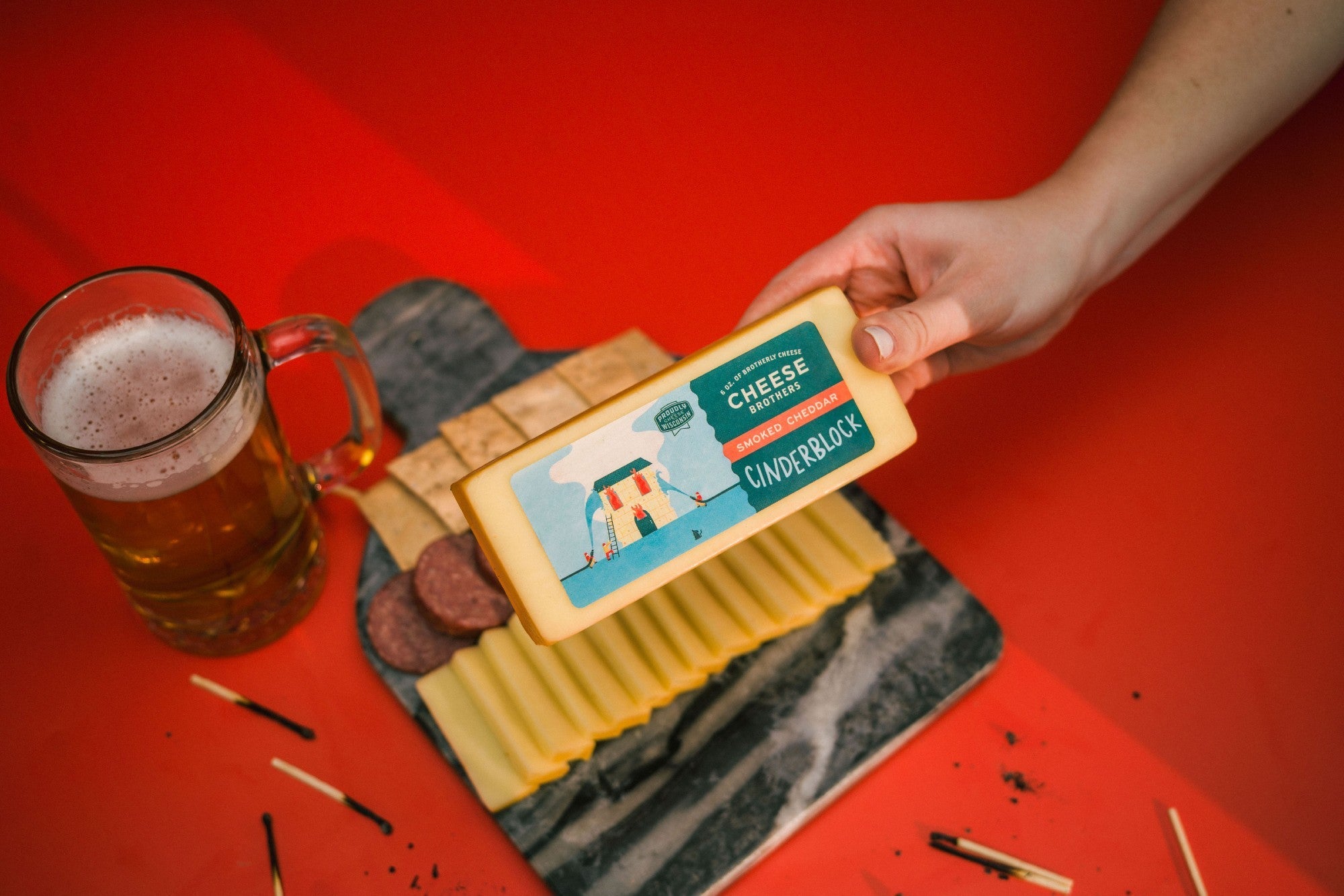 Smoked cheddar cheese block from Cheese Brothers, Inc. with a rich, golden-brown exterior and smooth, firm texture.