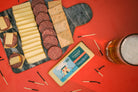 Slices of smoked cheddar cheese from Cheese Brothers, Inc., displayed on a wooden board with a rustic background.