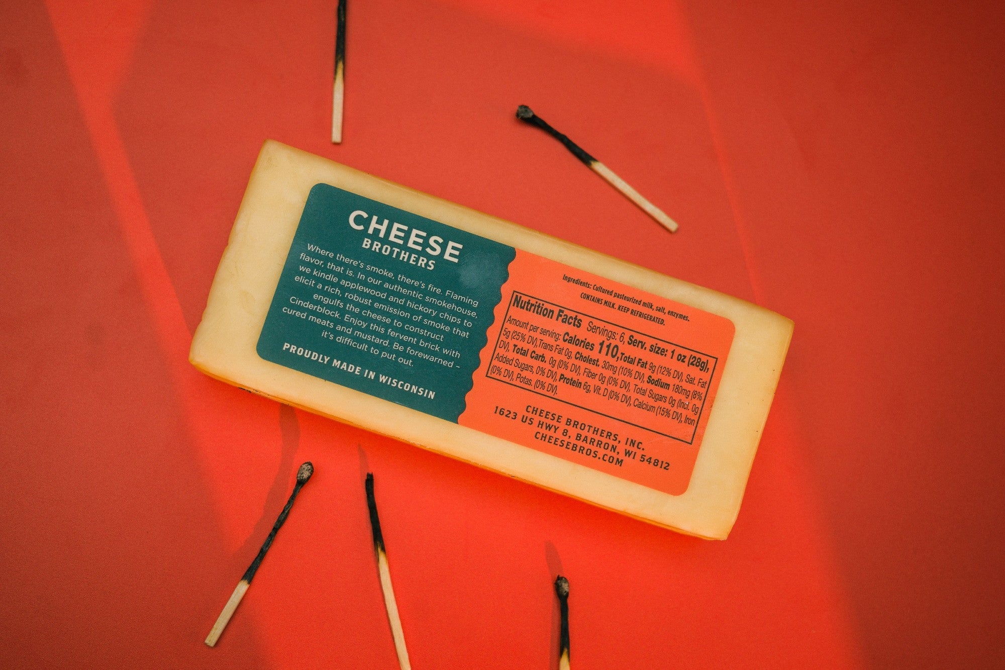 A block of smoked cheddar cheese from Cheese Brothers, Inc., showcasing its rich, smoky flavor and creamy texture in a close-up view.