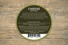 Slices of smoked mozzarella cheese from Cheese Brothers, Inc., arranged on a wooden board with a rustic background.
