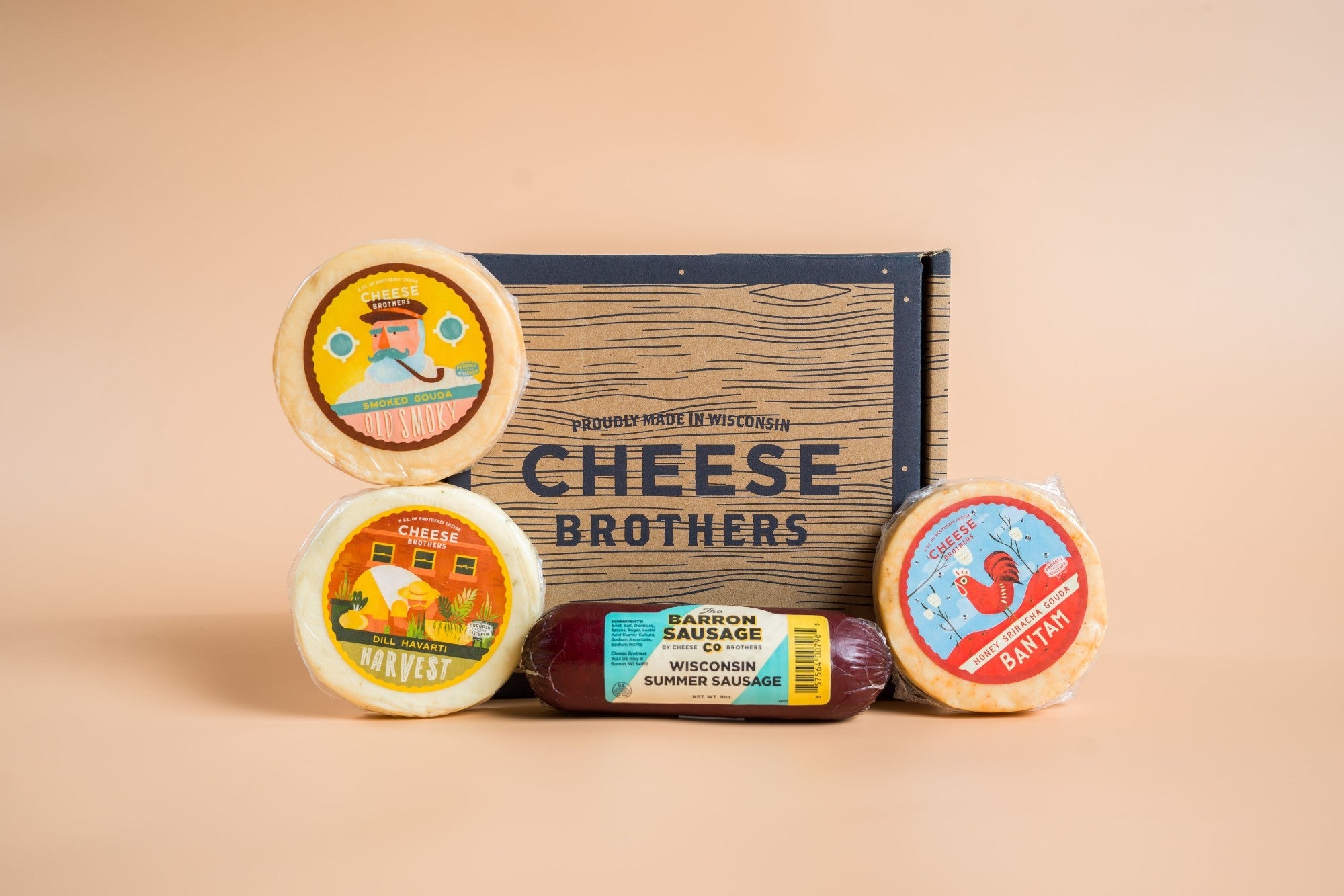 Assorted cheese and sausage sampler pack from Cheese Brothers, Inc., featuring various cheeses and cured sausages arranged on a wooden board.