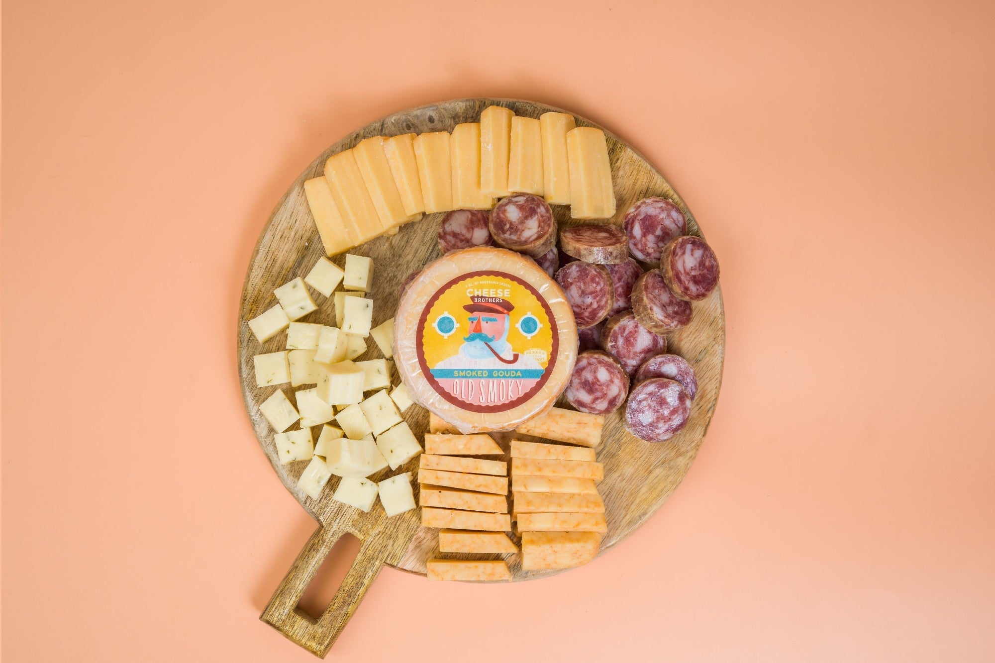 Cheese Brothers, Inc. meat and cheese sampler featuring four assorted cheeses and cured sausages on a wooden platter.