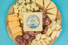 Cheese Brothers Deluxe Charcuterie Pack with cured meats, cheeses, nuts, and accompaniments arranged on a wooden board.