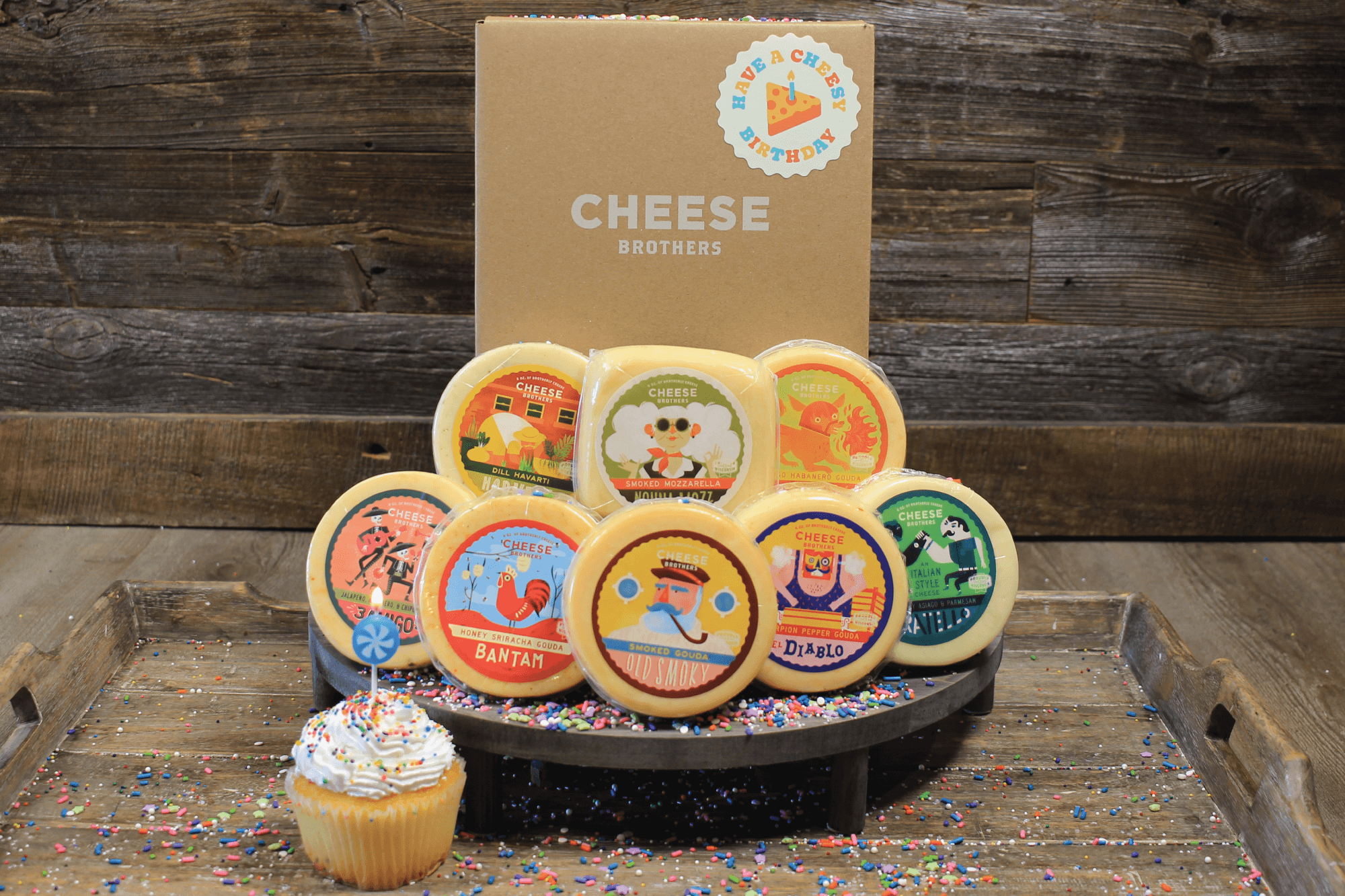 Cheesy Birthday gift basket from Cheese Brothers, Inc. with assorted cheeses, snacks, and birthday-themed items in a colorful box.