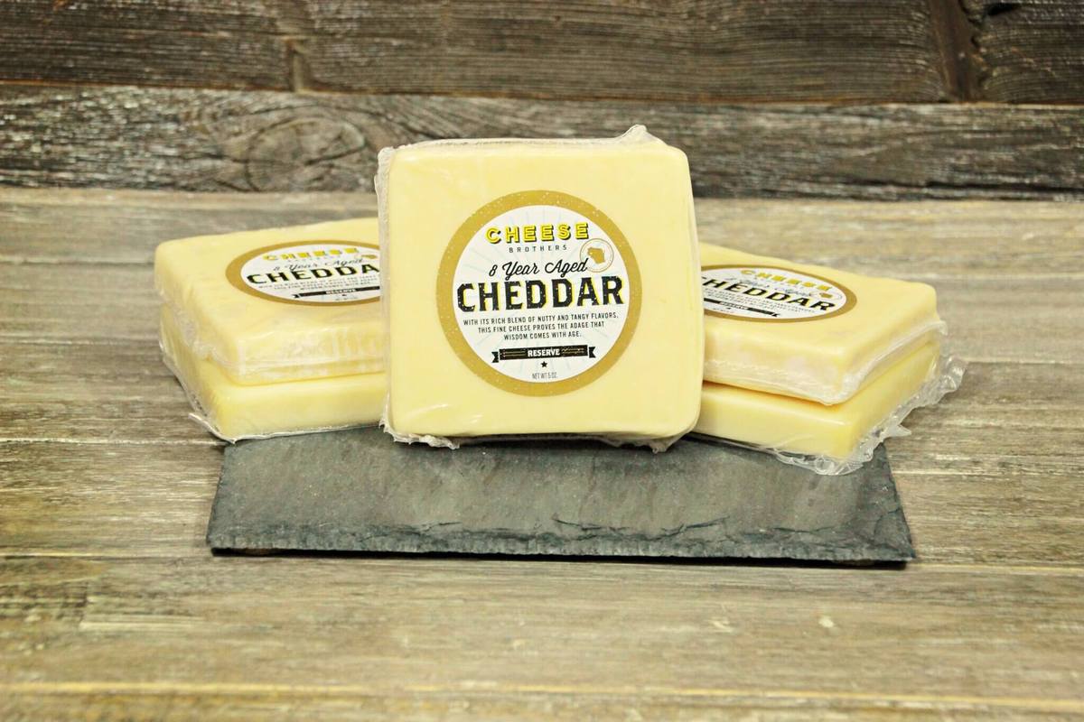 Cheese Brothers Inc. gift basket featuring aged 8-year cheddar cheese, crackers, and gourmet snack items in a decorative bundle.