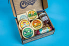 Assorted cheese and cured meats in a charcuterie box from Cheese Brothers, Inc., featuring nuts, fruits, and gourmet accompaniments.