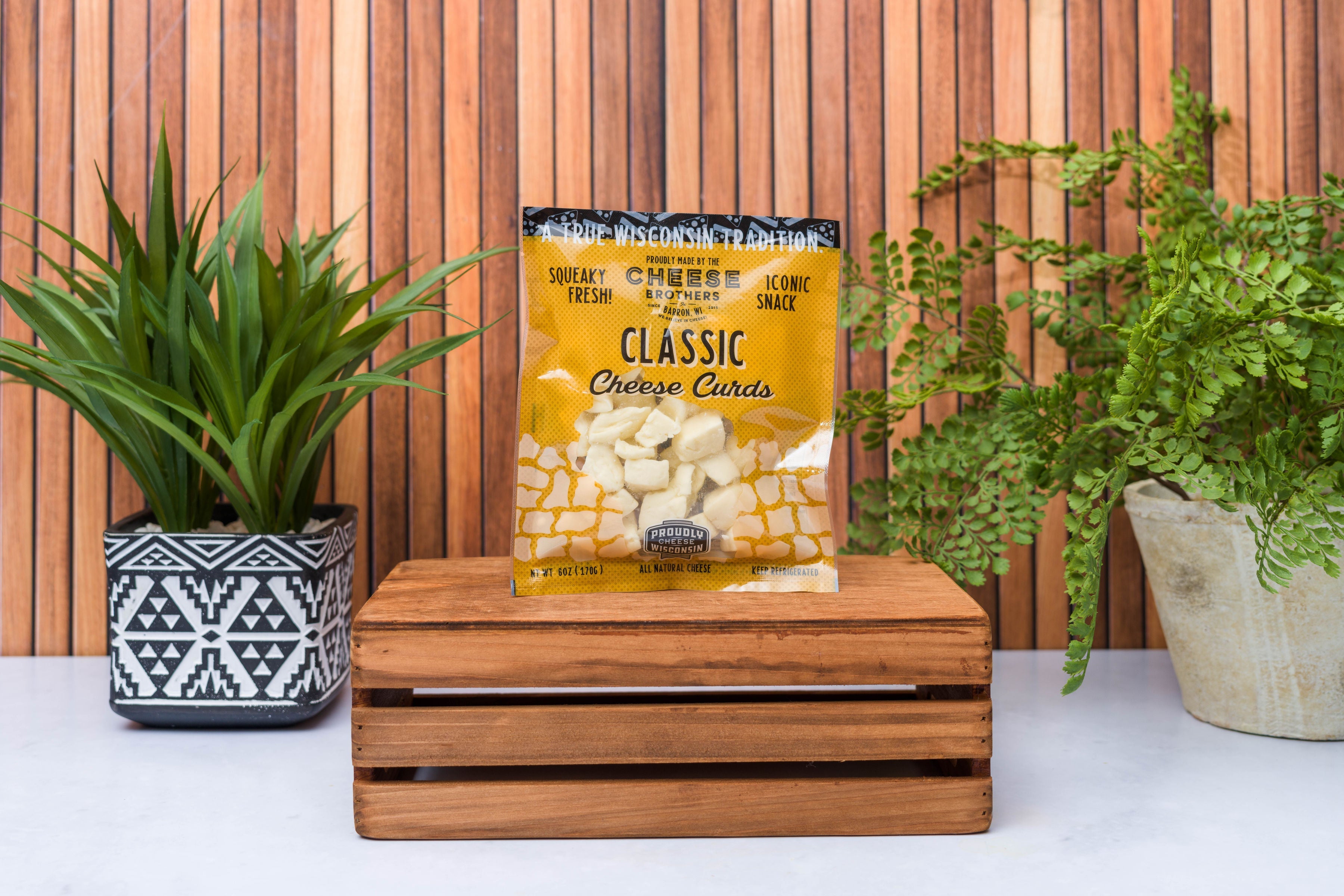 Assorted Wisconsin Cheese Curds Sampler 8-Pack from Cheese Brothers, Inc., showing fresh, golden cheese curds in a gift bundle.