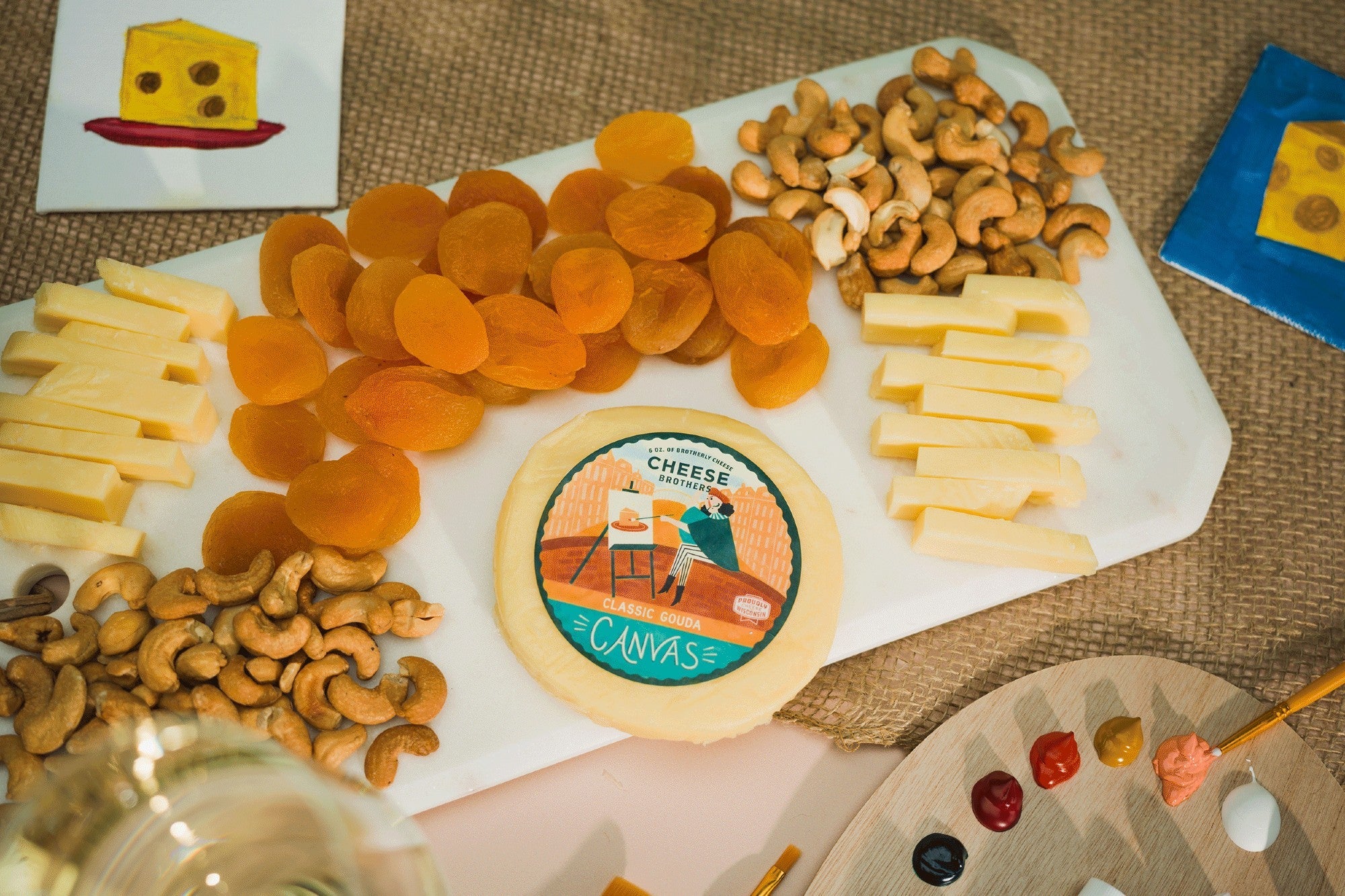 Creamy Classic Gouda cheese from Cheese Brothers, Inc., featuring a smooth, golden-yellow wheel on a wooden cheese board.