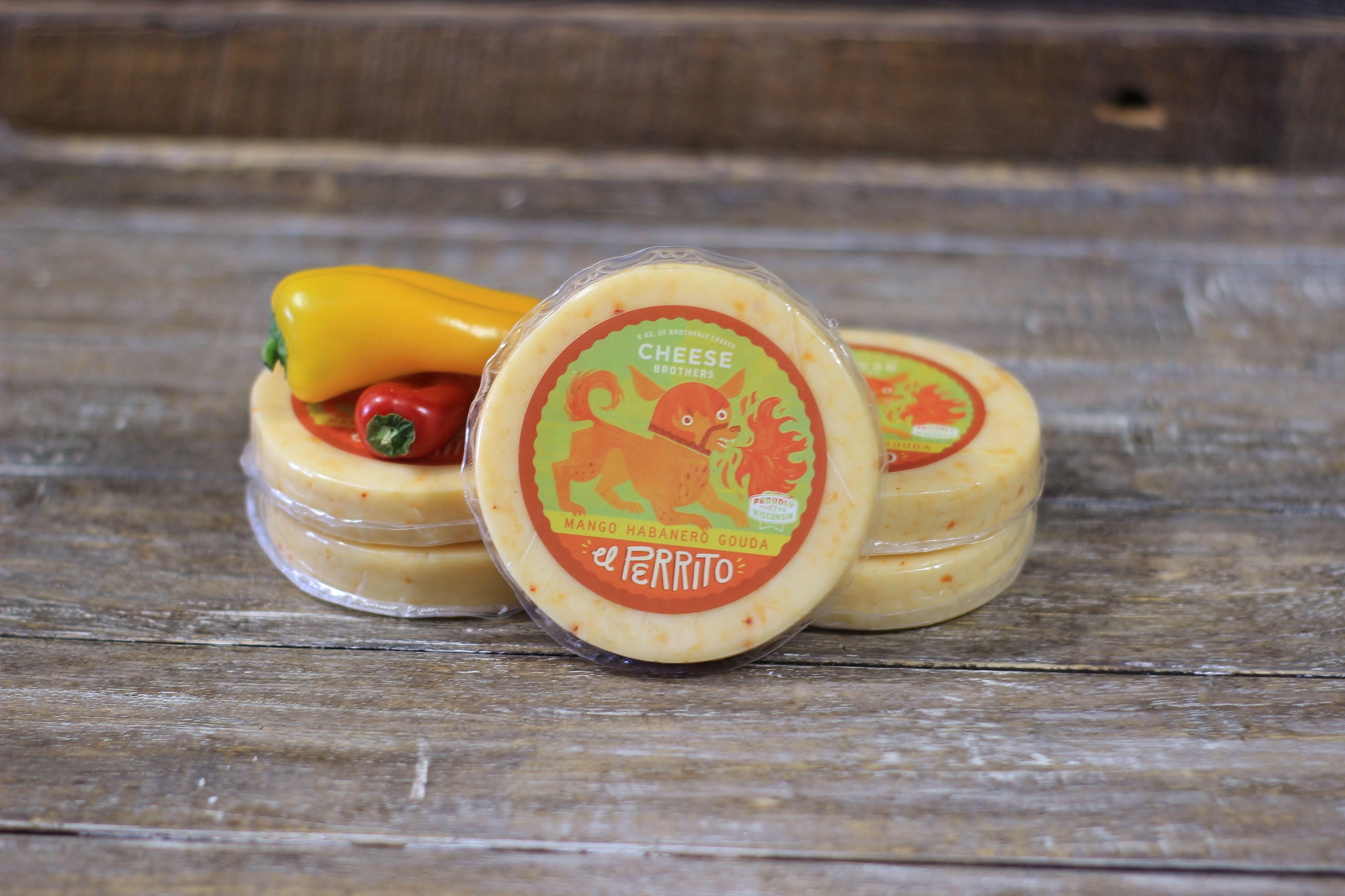 Mango Habanero Gouda cheese block from Cheese Brothers, Inc., showcasing smooth gouda with mango and habanero peppers.