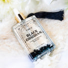 Black obsidian gemstone ritual oil bottle from Circe Boutique, featuring dark, glossy black obsidian stones in a glass container.