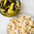 Dill pickle flavored popcorn by Colorado Popcorn Company in a 2 oz bag, featuring green popcorn with pickle seasoning.