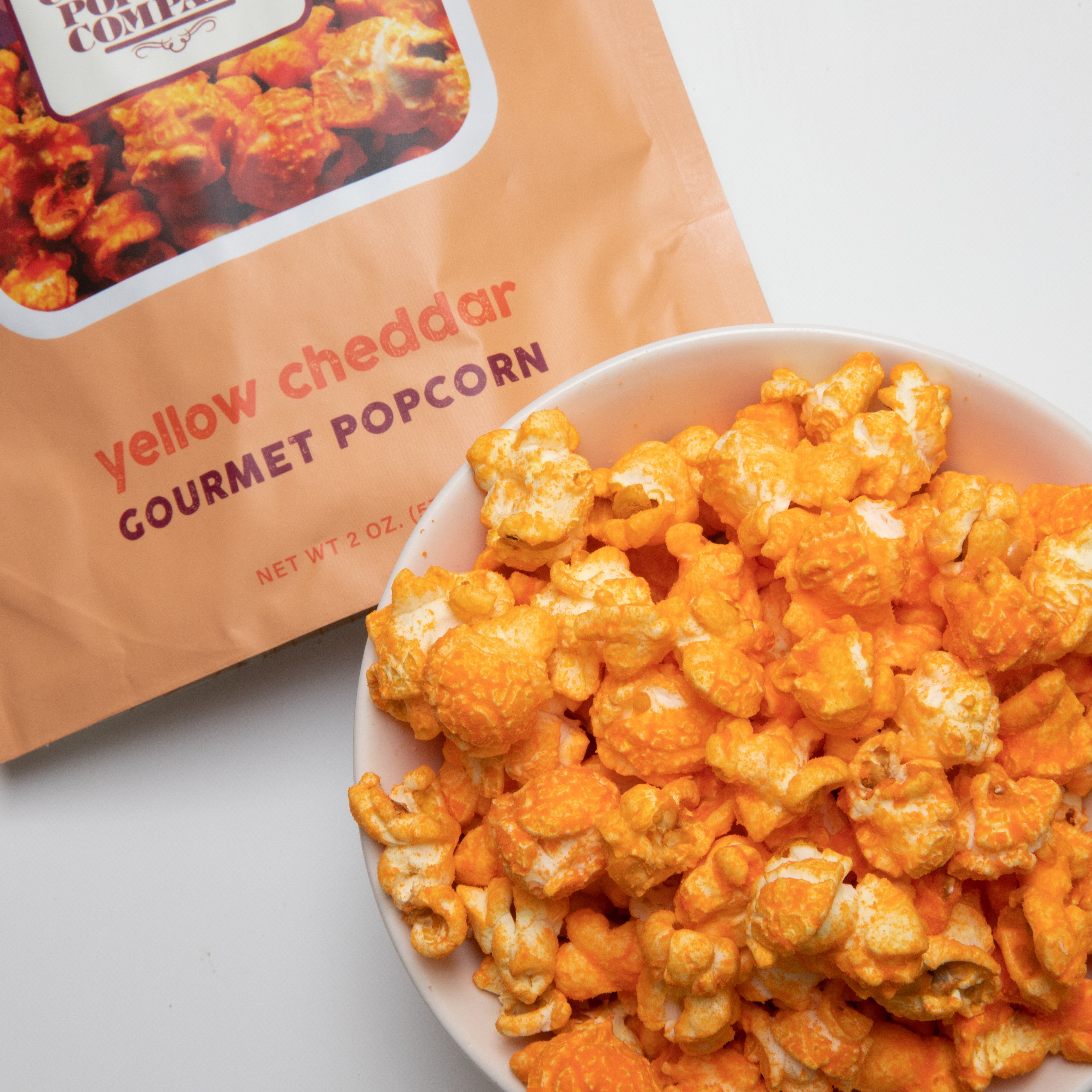 Yellow Cheddar popcorn from Colorado Popcorn Company in a 2 oz bag, featuring bright yellow cheese-coated popcorn kernels.